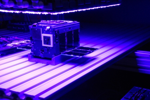 One of the AeroCube-10 cubesats undergoes testing in Aerospace's solar simulator laboratory in El Segundo, Calif. (Credit: The Aerospace Corporation)