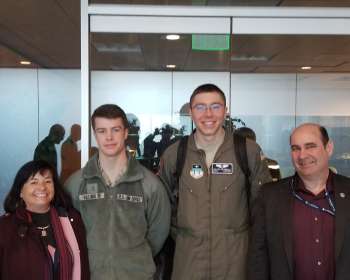 Four people standing together posing for photo.