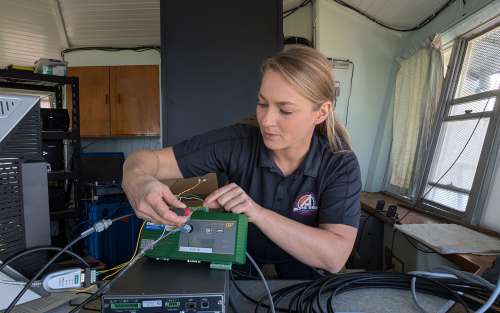 Aerospace international partnerships project leader Ashley Kowalski adjusts wiring of weather monitoring technology