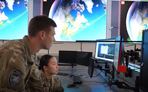 Many in army uniform looking at screen with earth on it.